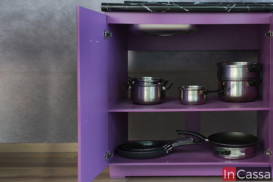 Se presenta el mueble de tarja inferior en color uva en su totalidad, diseñado para almacenamiento eficiente de ollas, sartenes y otros utensilios de cocina. La imagen destaca la capacidad y funcionalidad del espacio, complementado con una elegante cubierta de formaica en estilo mármol negro.