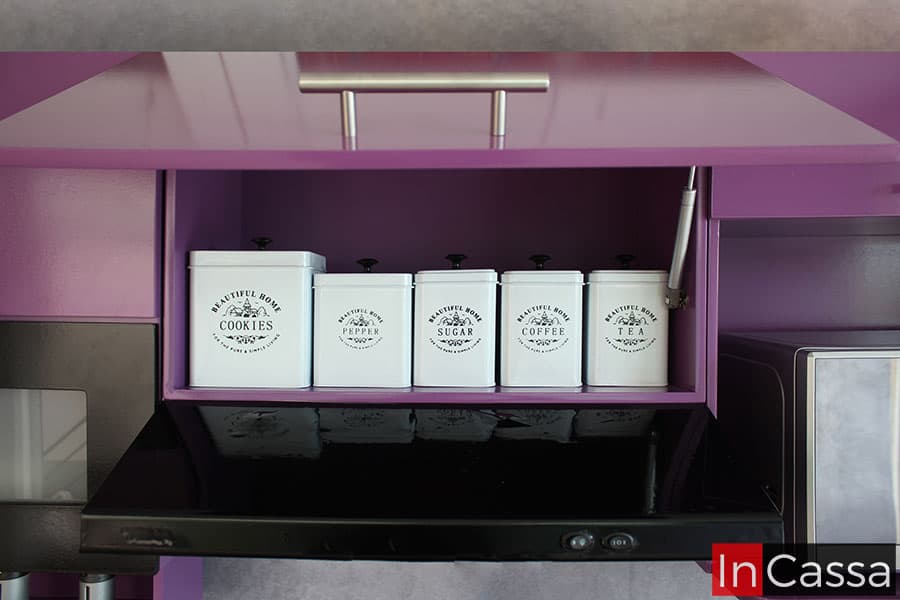 La imagen presenta el mueble sobre campana incluido en la cocina, en el cual puede encontrarse un amplio compartimento cuyo interior es de color uva, al igual que su estructura exterior, además también cuenta con una puerta de apertura y cierre vertical gracias a sus pistones neumáticos integrados.