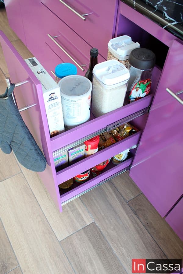 Está toma se enfoca en el especiero integrado al módulo inferior largo de la cocina, esté cuenta con 3 espacios largos que mantienen en su interior el mismo tono uva que las partes exteriores del mueble. Además el especiero cuenta con un sistema de rieles metálicos integrados para su apertura y cierre.