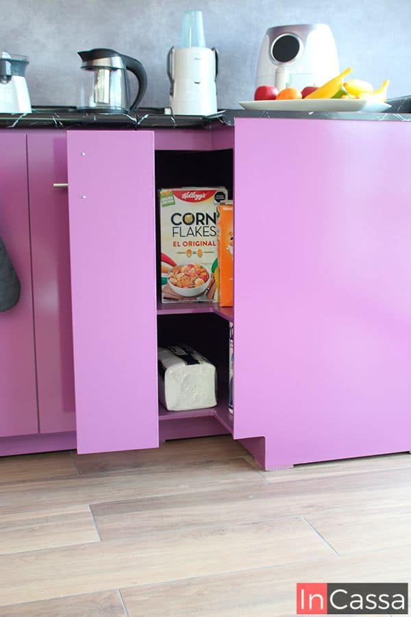 Se muestra el compartimento interior del gabinete esquinero inferior incluido en la cocina, este cuenta con dos espacio divididos por un entrepaño horizontal, conservando el color uva tanto en su estructura interna como externa, además de que también cuenta con una cubierta de formaica estilo mármol negro.