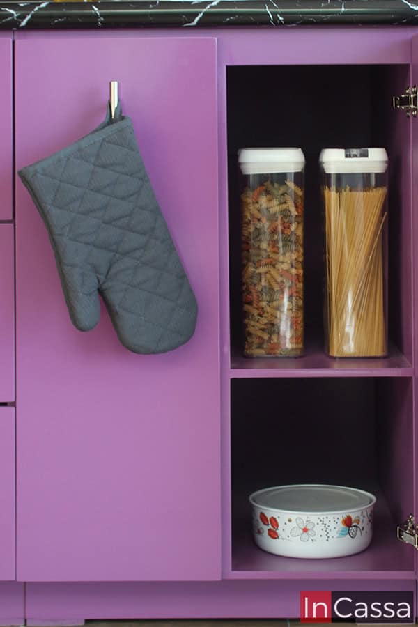 Compartimento en color uva perfecto para almacenar alimentos y utensilios de cocina, con un diseño abierto que facilita el acceso a los productos esenciales. Incluye un espacio adicional para colgar accesorios como guantes de cocina, optimizando la organización y funcionalidad del área.