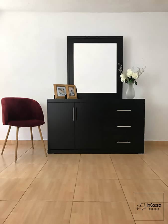 La imagen muestra el tocador Croacia desde un ángulo frontal, con acabado en color chocolate, espejo amplio, tres cajones con jaladeras metálicas y puertas centrales. Acompañado por una silla tapizada en tono vino.