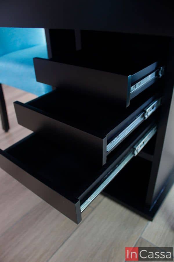 Observamos una toma concentrada en los 3 cajones incluidos en la estructura del pedestal de la mesa. Quedando a la vista su interior el cual conserva el color chocolate presente en toda la mesa. Sin mencionar que podemos ver a detalle su sistema de apertura y cierre, el cual consta de rieles metálicos incorporados en la construcción de cada cajón.