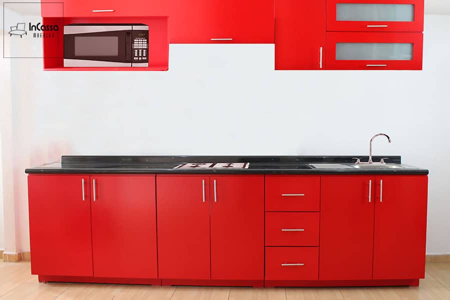 La foto presenta una cocina modular en un vibrante tono rojo, equipada con cajones, puertas y alacenas superiores, ofreciendo un diseño moderno y amplio espacio de almacenamiento.