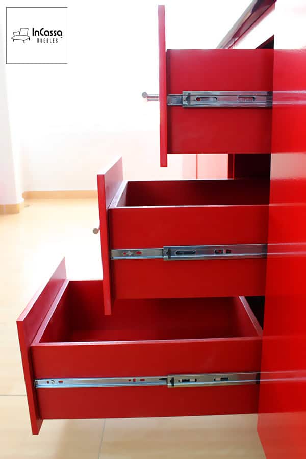 La foto presenta un sistema de tres cajones rojos completos con rieles metálicos de alta calidad, permitiendo un movimiento fluido y maximizando el almacenamiento en la cocina.