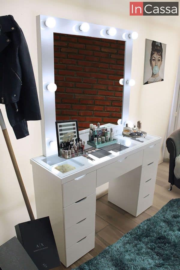 Tocador tipo vanity con 8 focos incluidos en su amplio espejo, el mueble cuenta con 8 cajones pequeños y uno más grande en el centro. La iluminación de los focos hace más notable su cubierta de cristal con la cuál se hacen perfectamente visibles los utensilios guardados en los 3 cajones superiores.