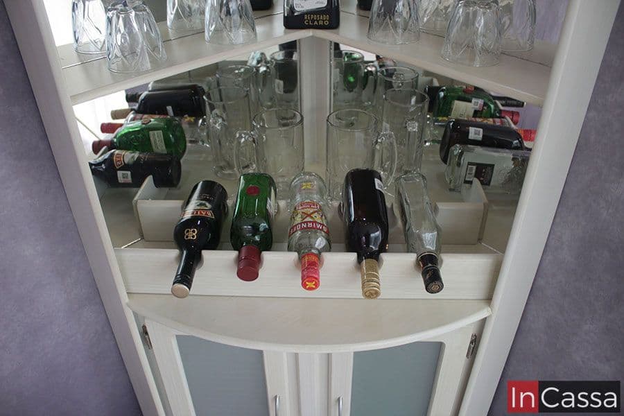 Los compartimentos inferiores de este elegante mueble de bar están diseñados para organizar botellas de manera eficiente, ofreciendo un acceso fácil y una presentación ordenada. La combinación de espejos y estantes resalta las botellas, creando un espacio visualmente atractivo y funcional para almacenar y exhibir tanto bebidas como vasos. Este diseño se complementa con puertas de panel translúcido, añadiendo un toque de sofisticación al conjunto.