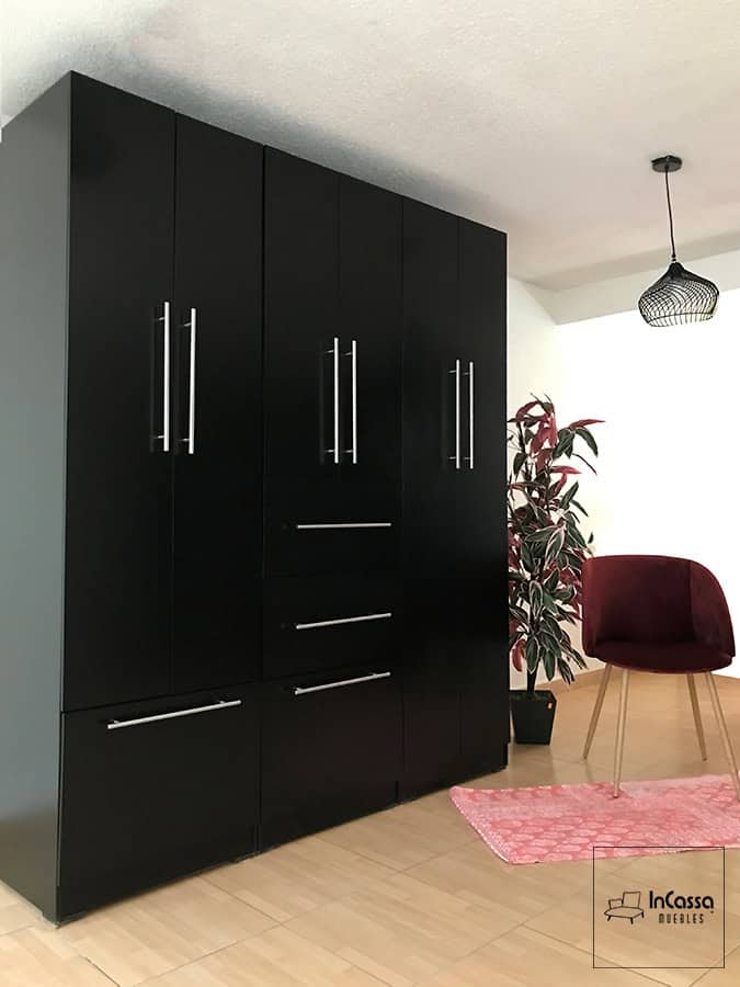 El clóset se muestra desde una toma lateral, en la que se destaca su gran longitud y el gran numero de compartimentos con los que cuenta. La estructura completa del mueble tiene un acabado chocolate mate, y cada una de sus puertas y cajones cuenta con jaladeras de barra T metálica.