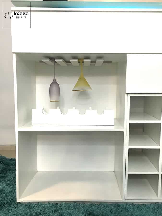 En esta toma frontal se observa el interior de la cantina blanca, equipada con soportes superiores para copas colgantes, un módulo central para botellas y compartimentos laterales. El diseño funcional y moderno optimiza el almacenamiento en espacios reducidos.