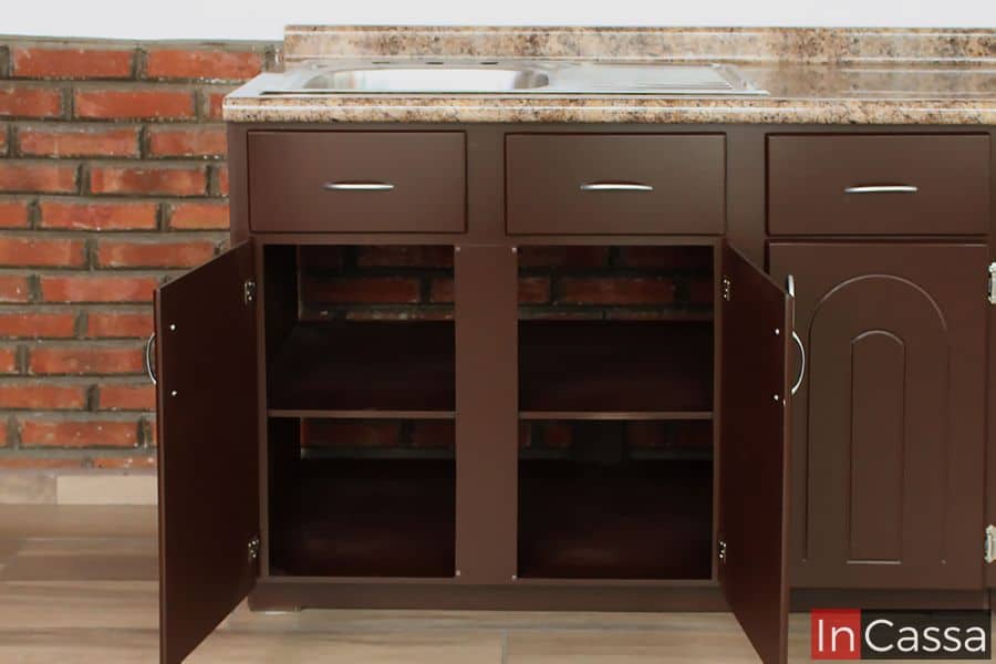 Foto del módulo de tarja de la cocina en acabado café completo, con puertas dobles y repisa interna, ofreciendo un amplio espacio para almacenamiento, perfecto para organizar utensilios grandes o productos de limpieza. Los cajones superiores decorativos agregan un toque de elegancia al diseño.