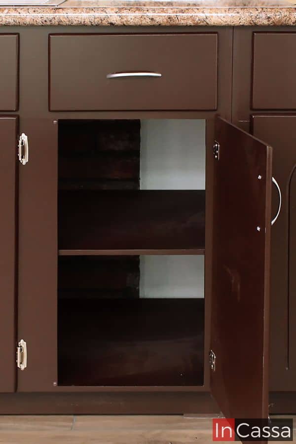 Este compartimento inferior en color café completo, con una repisa ajustable, proporciona un almacenamiento flexible, ideal para guardar diversos utensilios de cocina o productos de limpieza, manteniendo todo al alcance y organizado.