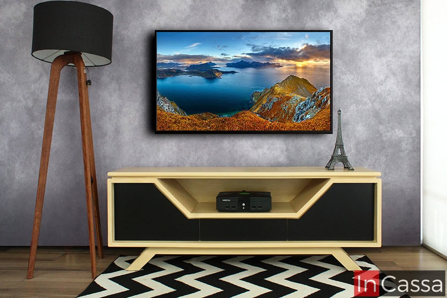 La imagen muestra el mueble de TV modelo Escandinavia en una toma frontal, fabricado en MDF con acabado en tono natural y frentes en color chocolate mate. Su diseño minimalista destaca por las líneas geométricas en las puertas y el espacio central para dispositivos, ideal para salas modernas y funcionales.