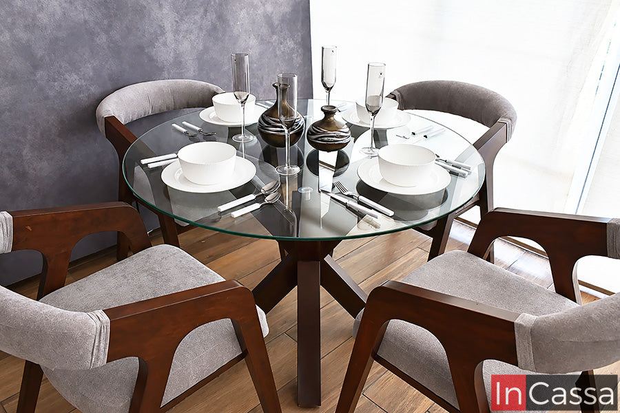 En un acercamiento que resalta cada detalle, el Comedor Redondo Viral en Pinterest FORMENTERA con Mesa de Vidrio muestra su acabado en color tabaco y sillas tapizadas en suede gris perla. La cubierta de vidrio deja visible su distintiva base central y el diseño curvo de las sillas.