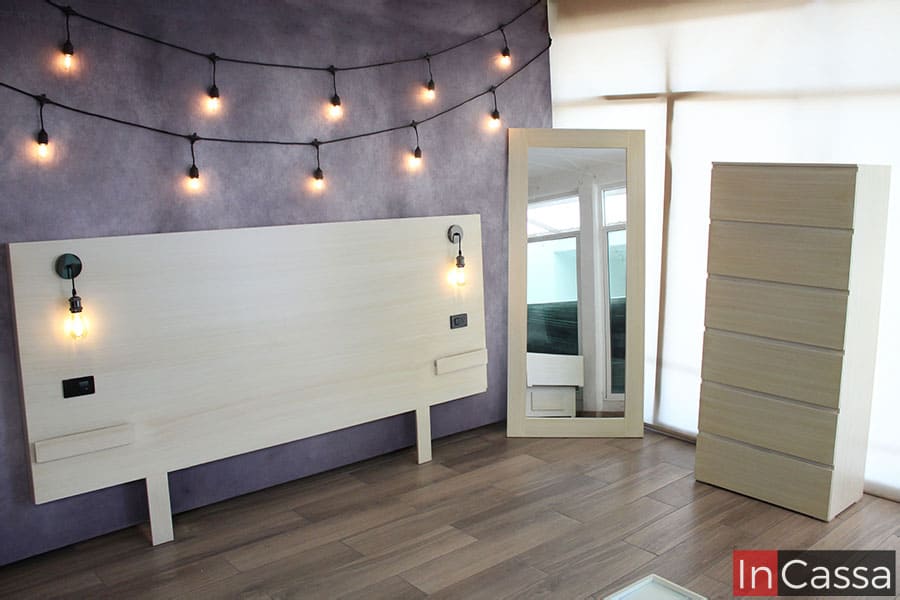 En esta imagen se muestra en conjunto la cajonera, el espejo y la cabecera de la recámara, en está ultima puede apreciarse sus dos lampara minimalistas y las contras con las que cuenta para instalar los buroes flotantes. Todas las partes exhibidas en la foto tienen el mismo acabado paja laqueado.