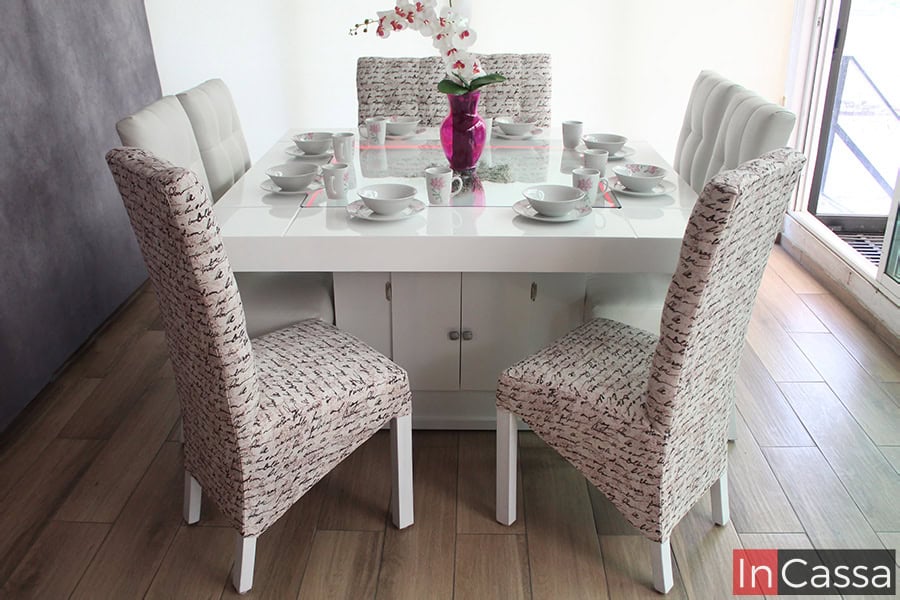 Moderno Comedor color blanco con 8 sillas tapizadas instalado en una habitación con ventana completa. El comedor destaca por su mesa con arenero y pedestal con compartimento integrado.
