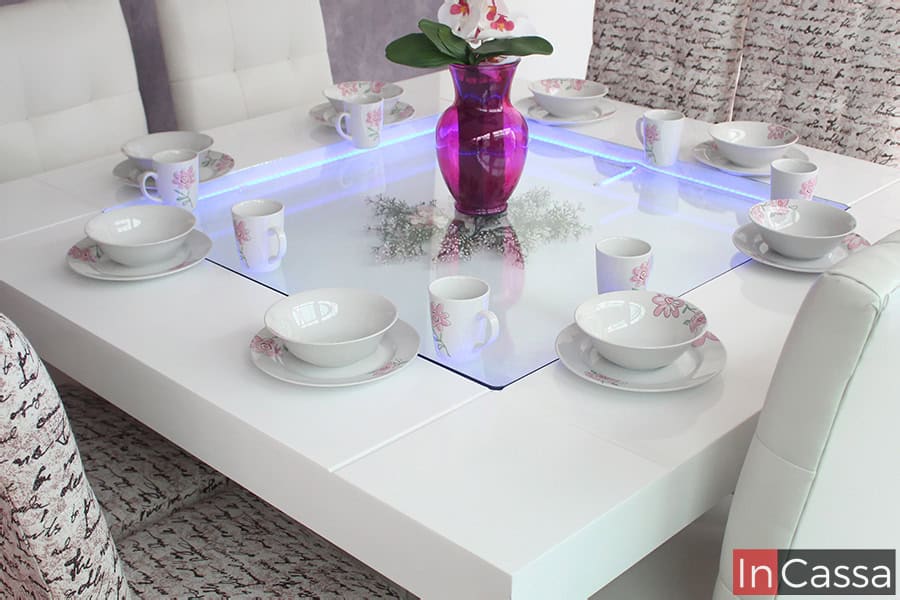 Esta toma se enfoca en el arenero del comedor para 8 personas, el cuál funciona como un centro de mesa que además proporciona iluminación LED de diferentes colores. La mesa se muestra decoradas con distintas vajillas y un bonito florero.