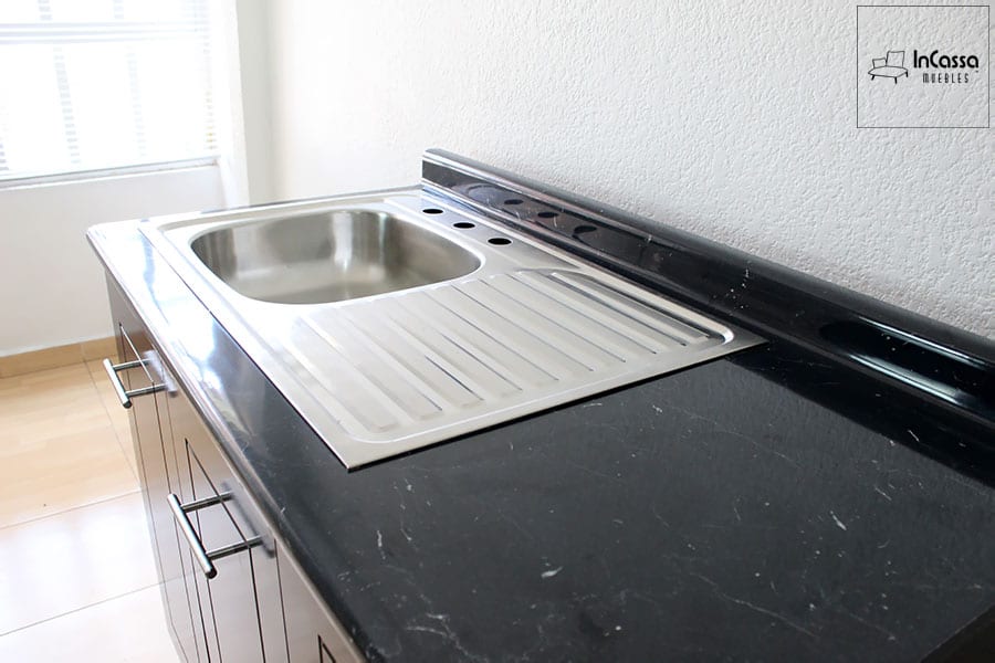La foto muestra la hermosa cubierta de formaica en estilo mármol negro incluida en la cocina, que ofrece una superficie duradera y de fácil limpieza. El fregadero de acero inoxidable con escurridor integrado añade funcionalidad y un toque moderno al diseño. Este conjunto es ideal para cualquier cocina que busque combinar estilo y practicidad.