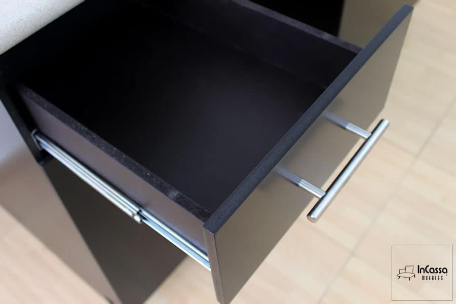 La imagen muestra un cajón abierto visto desde arriba, donde se aprecia la corredera metálica lateral, el acabado chocolate elegante del interior y la jaladera cilíndrica en acero inoxidable, que destaca por su estilo moderno y funcional.