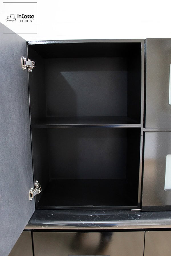 La imagen muestra una alacena en acabado negro con puerta abatible y bisagras metálicas reforzadas. Su diseño cuenta con un estante interno que permite organizar diversos utensilios de cocina, maximizando el almacenamiento y brindando un estilo moderno y funcional.