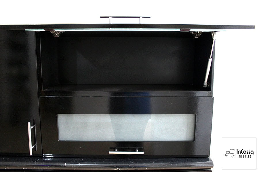 La foto presenta una alacena superior en color negro con un compartimento superior de apertura vertical asistida por pistón neumático. Debajo, se encuentra un módulo con puerta de vidrio esmerilado y jaladera metálica, combinando funcionalidad y diseño moderno para optimizar el almacenamiento en la cocina.