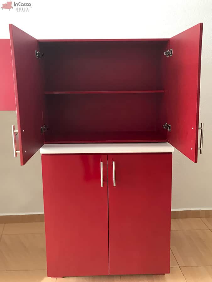 La imagen presenta la alacena superior de la cocina HAMPTON para estufa con puertas abiertas, revelando un compartimento dividido con entrepaño, además también se muestra el gabinete inferior de doble puerta, ambos equipados con jaladeras metálicas y amplio espacio de almacenamiento, además de compartir un acabado rojo quemado.