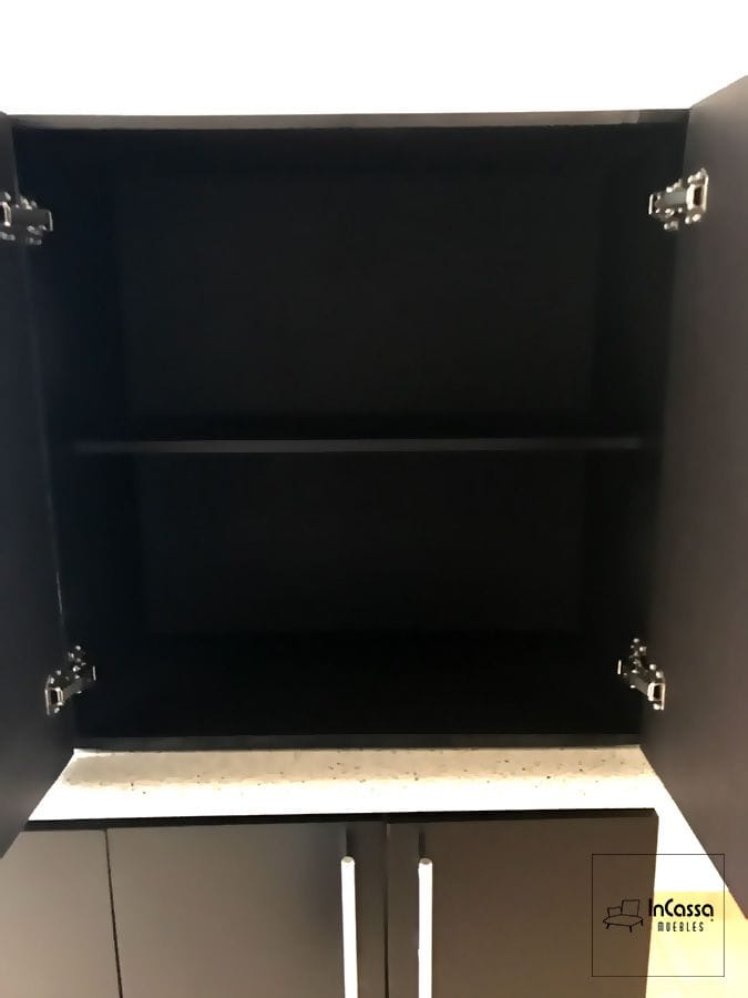 Vista interior de una de las alacenas superiores de la cocina, con un estante intermedio para maximizar el almacenamiento. Las puertas cuentan con bisagras metálicas que aseguran un cierre suave y duradero. El acabado en chocolate mate completo aporta un estilo sofisticado y contemporáneo, ideal para una organización eficiente de utensilios y suministros de cocina.