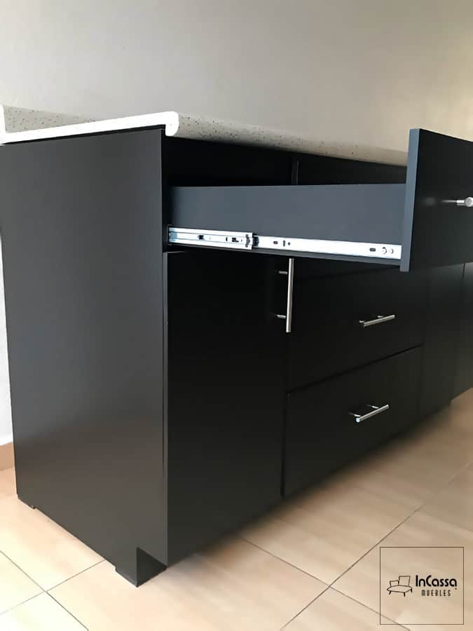 Detalle de los cajones de la cocina en color chocolate mate completo, con un sistema de rieles metálicos para un deslizamiento suave y silencioso. La cubierta de formaica y las jaladeras metálicas realzan el diseño moderno y elegante. Ideal para un almacenamiento organizado y accesible.