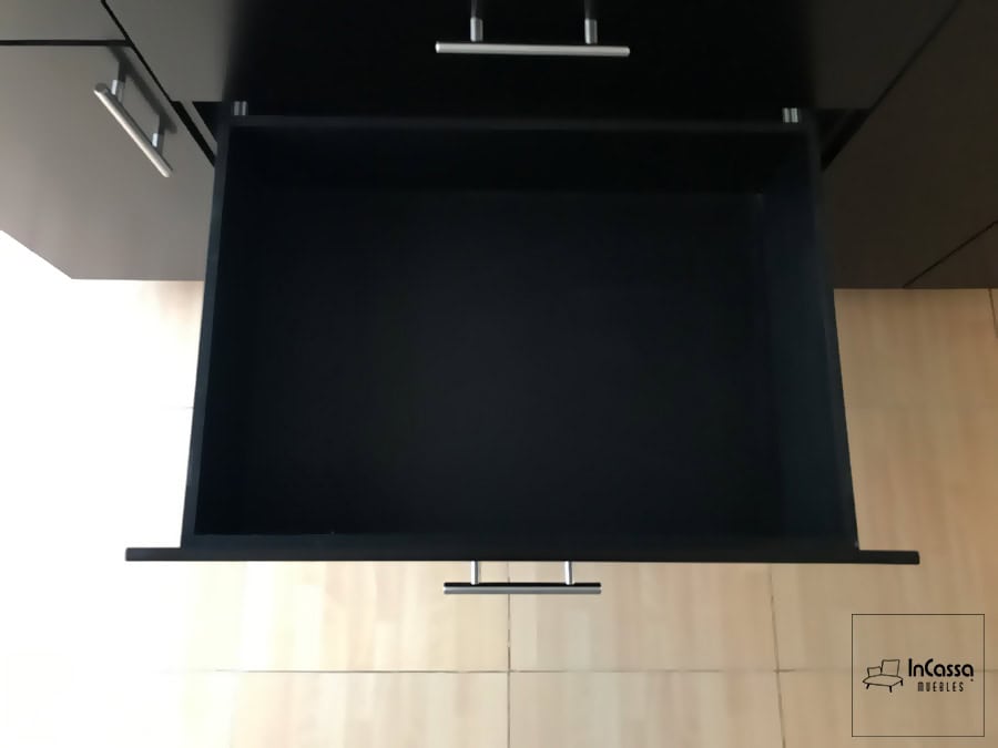 Vista interior de uno de los cajones de la cocina, mostrando su amplio espacio de almacenamiento. El diseño es ideal para organizar utensilios de cocina y otros artículos. Los acabados en chocolate mate y las jaladeras de barra metálica aportan un estilo moderno y elegante.