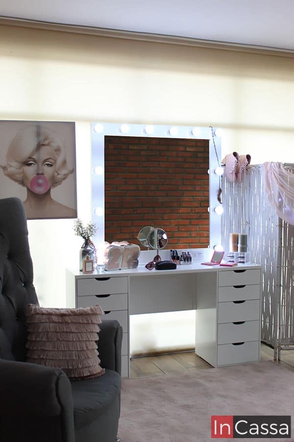 La imagen muestra el tocador tipo Vanity tamaño JUMBO en color blanco completo, resaltando el brillo de los 12 focos LED incorporados en el espejo incluido en el tocador. Además es posible ver una amplia variedad de utensilios que además de resultar una excelente decoración para la toma, también nos da una idea de la gran longitud de la estructura.