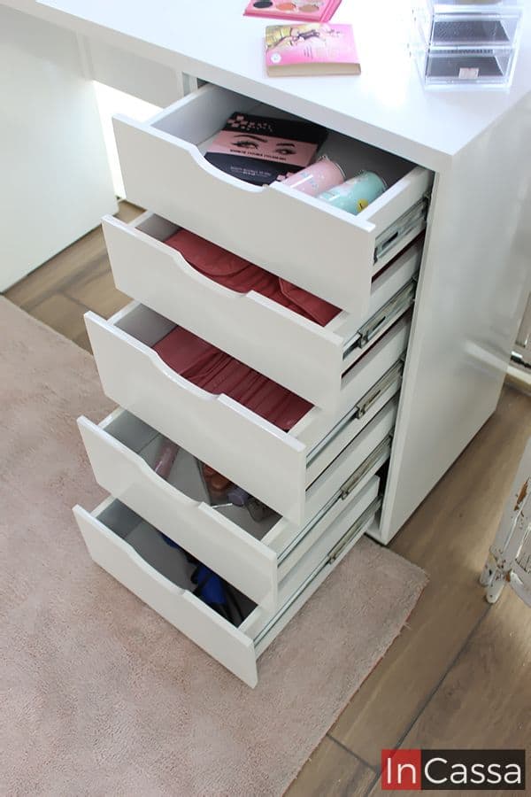 Es posible observar la estructura de los cajones del tocador más a detalle, estos tienen un tono blanco completo al igual que el resto del mueble; además se puede visualizar el sistema de apertura y cierre, el cual consta de rieles metálicos, incorporado a cada cajón, además de las prendas y utensilios que pueden almacenarse en el interior de cada uno.