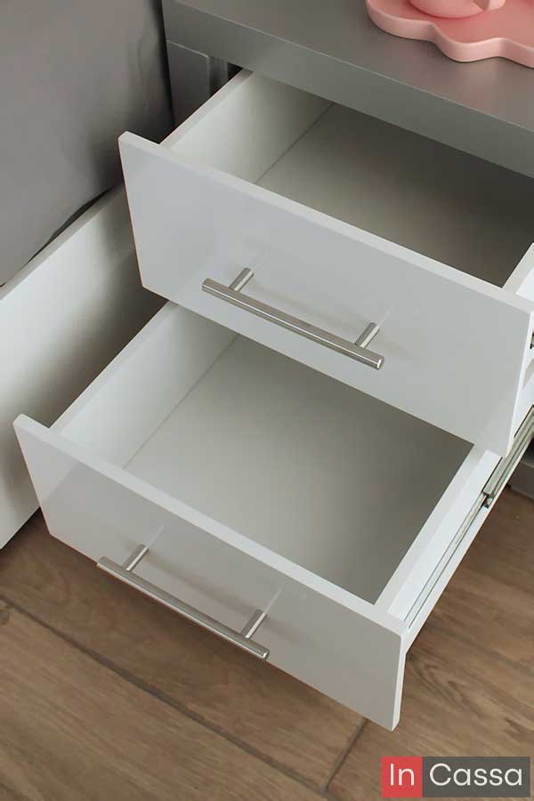 Una toma superior revela el interior del buró silver con ambos cajones blancos completamente abiertos. Las jaladeras metálicas y los acabados en blanco brillante destacan su diseño moderno y funcional, ideal para mantener el orden junto a la cama.