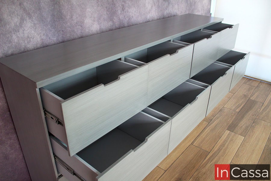 Una toma lateral de la cajonera que se concentra en los 8 cajones superiores, los cuales a pesar de ser más pequeños que los inferiores cuentan con una buena capacidad de almacenamiento, y además en su interior mantienen un tono gris igual al de la estructura externa del mueble.