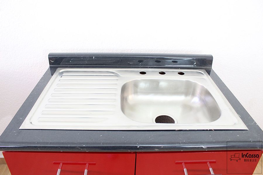 La fotografía muestra una tarja de tina sencilla con escurridor integrado en acero inoxidable, montada sobre una cubierta de formaica en estilo mármol negro. Su diseño funcional y elegante se complementa con perforaciones listas para instalación de mezcladora.