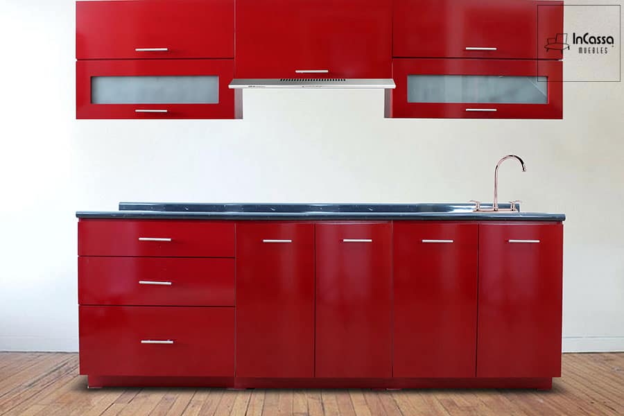 Esta cocina integral combina elegancia y funcionalidad, con módulos superiores e inferiores en tono rojo quemado brillante, jaladeras metálicas y cubierta en estilo mármol color negro. El diseño incluye tarja y espacio para campana, ideal para una cocina moderna y llamativa.