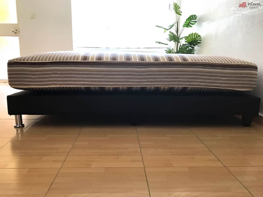 En esta toma lateral podemos ver el largo completo del colchón hotelero, lo que nos facilita determinar su longitud y la densidad de su acolchonado, cuyo tapiz presenta un estilo de rayas.