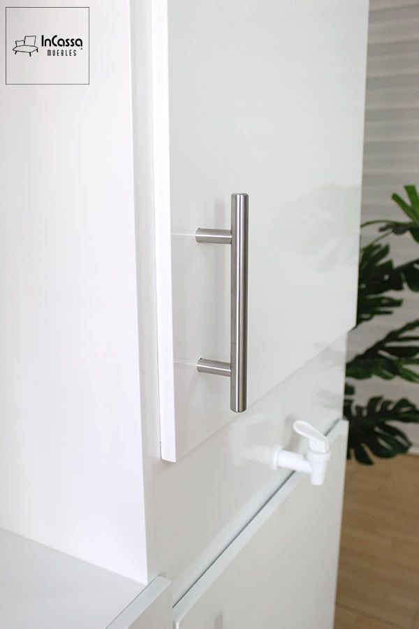 La fotografía presenta un acercamiento lateral de la Alacena para Microondas Modelo HOUSTON, donde destaca la jaladera tubular de acero inoxidable y el impecable acabado blanco brillante. El enfoque resalta la calidad de los materiales y el toque moderno que aportan sus herrajes y grifo lateral funcional.