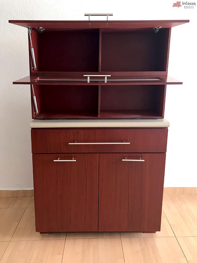 Se presenta el módulo superior abierto de la cocina integral en acabado maple oscuro completo. Este diseño resalta los compartimentos interiores divididos, ideales para organizar utensilios y accesorios de cocina. Los pistones hidráulicos aseguran un manejo suave y seguro de las puertas.