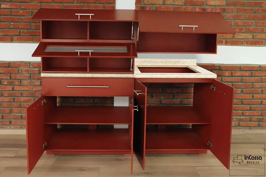 La foto nos muestra la cocina con todos sus compartimentos abiertos, en donde destaca la pintura maple la cuál esta presente tanto en las partes exteriores como en los interiores. También podemos observar el hueco para parrilla y parte de la cubierta de formica en estilo "ojo de pájaro".