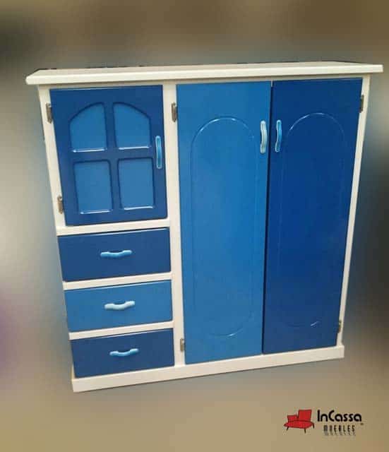 La fotografía muestra el Roperito Infantil Modelo ISAAC, con una encantadora estructura blanca que resalta sus tonos de azul claro y azul rey. Su diseño tipo casita incorpora cajones amplios, puertas con molduras decorativas y tiradores en tono celeste, aportando un estilo alegre y funcional ideal para dormitorios infantiles.