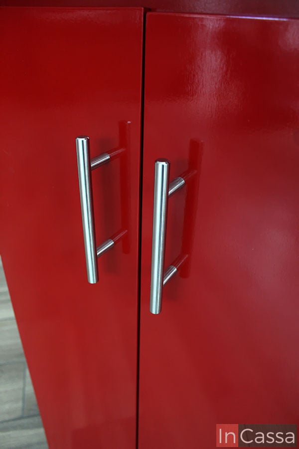 En esta imagen la mirada se concentra en las jaladeras incorporadas en cada una de las puertas traseras de la barra. Las jaladeras son totalmente metálicas con un diseño en "T" con acabado cromado. Además también tenemos una toma más cercana a las puertas de acabado rojo brillante.