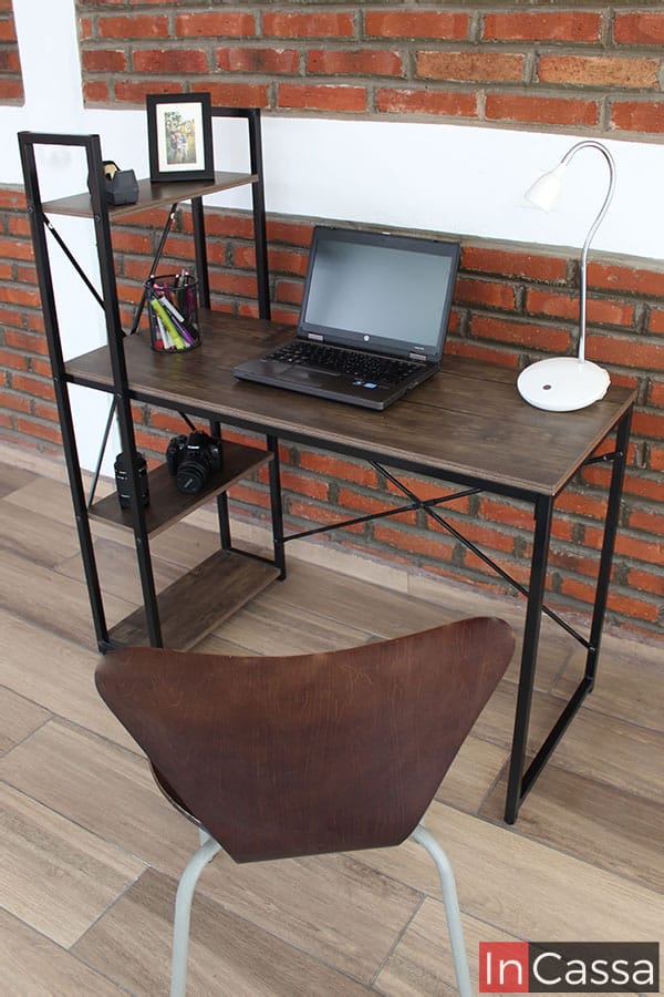 Observamos una toma superior del escritorio, en la que podemos ver de mejor manera la longitud de la cubierta y repisas de MDF, las cuales presentan un acabado laqueado, mientras que la base metálica que las sostiene esta construida por ligeras barras de color negro.