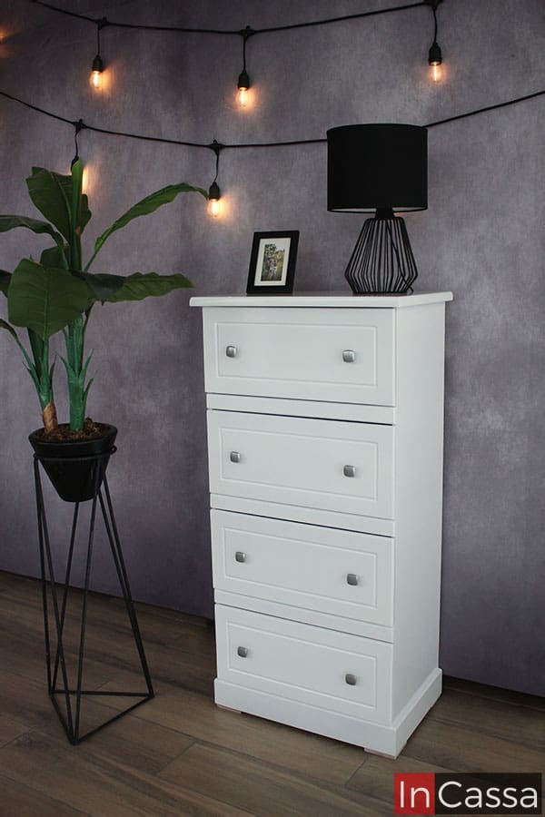 Bonita Cajonera de diseño infantil con cuatro amplios cajones, presentada en color blanco completo en una estancia con pared gris y piso de madera.