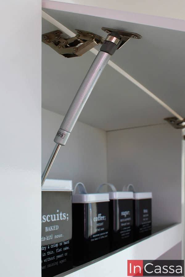 El módulo cuenta con un mecanismo de pistón neumático que facilita la apertura y el cierre suave de las puertas. Este detalle no solo mejora la funcionalidad, sino que también añade un toque moderno y sofisticado. El acabado blanco brillante completo y las bisagras reforzadas aseguran durabilidad y resistencia, complementando un diseño eficiente y elegante.