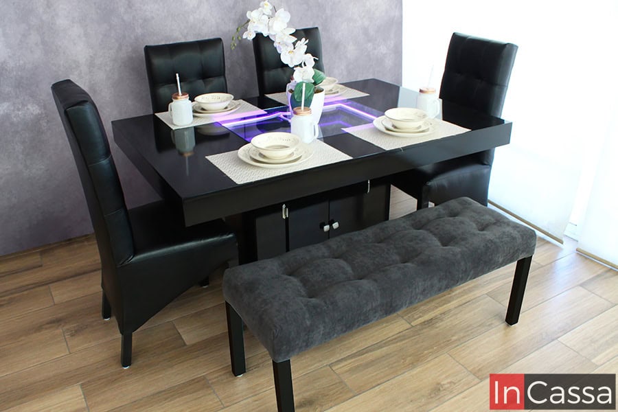 La imagen presenta el comedor que destaca por su diseño moderno y sofisticado. La mesa negra cuenta con un arenero con un sistema de iluminación LED integrado, y se encuentra acompañada por 4 sillas negras y una banca gris creando un ambiente acogedor y contemporáneo ideal para reuniones familiares o con amigos.