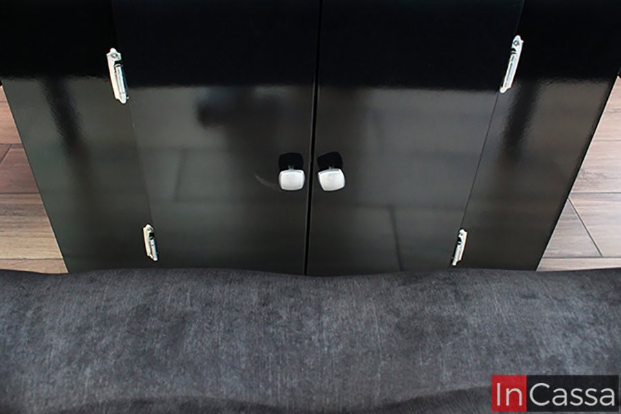 La foto resalta los compartimentos inferiores de la mesa negra completa, diseñados para ofrecer almacenamiento adicional sin comprometer la estética. Las puertas con acabados brillantes y asas minimalistas son una muestra del diseño funcional de este modelo.