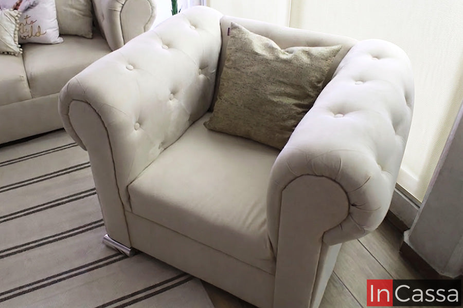 La imagen presenta el sillón individual de la Sala estilo Glam Modelo KÍROV tapizada en suede hueso, con elegante capitonado en respaldo y brazos curvos que aportan comodidad, suavidad visual y un estilo sofisticado al espacio.