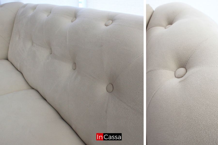 La imagen resalta los detalles capitoneados de la Sala estilo Glam Modelo KÍROV tapizada en suede hueso, mostrando la suavidad del tapiz, costuras decorativas y acabado elegante que aporta textura, confort y un estilo sofisticado al diseño.