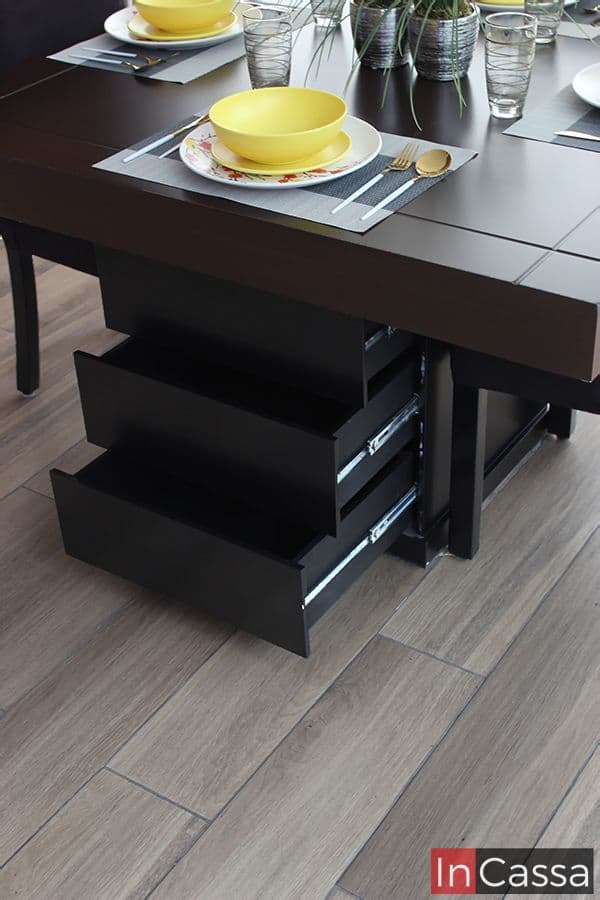 La foto se enfoca en la mesa del comedor de 4 sillas, dando una vista más cercana del acabado en su cubierta de color tabaco, además de mostrar los 3 cajones incorporados al pedestal de color chocolate de la mesa, estos cuentan con un sistema de apertura y cierre guiado por rieles metálicos.