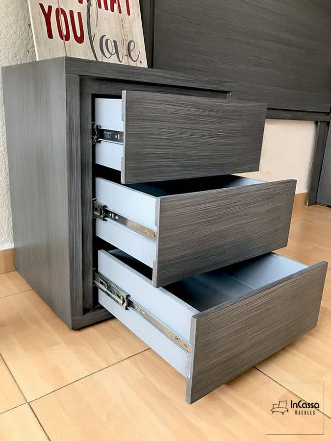 En esta imagen se muestra el buroe con sus cajones abiertos, equipados con correderas metálicas de extensión total, permitiendo un acceso cómodo y organizado a su interior; presentado en un elegante acabado gris cenizo oscuro completo.