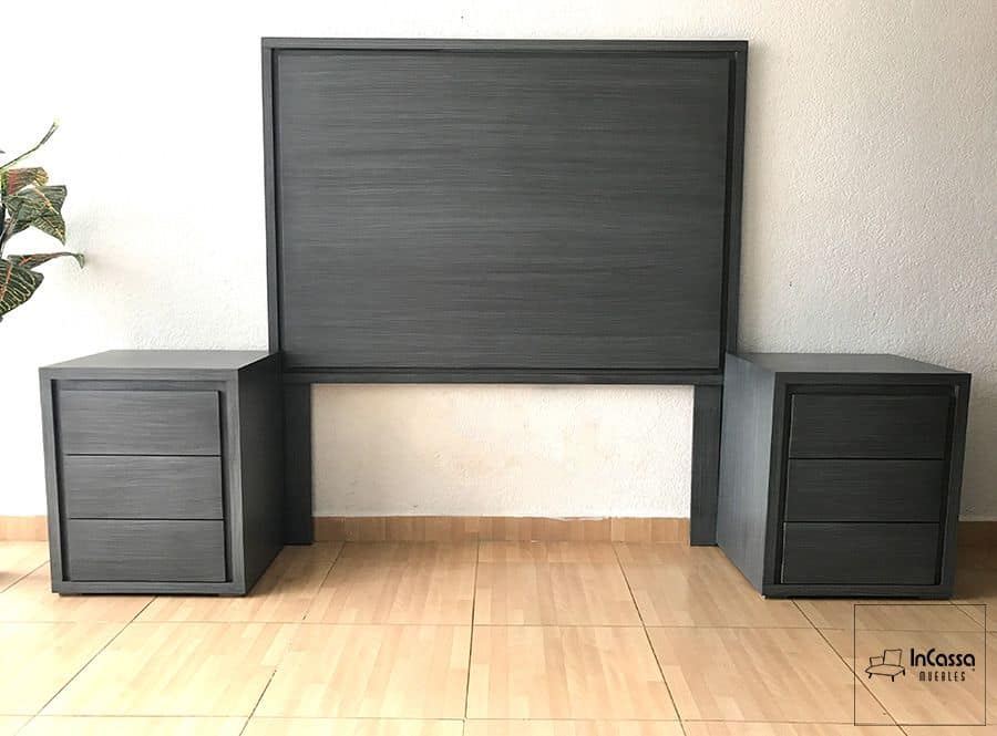 La foto muestra una cabecera de diseño minimalista en tono gris cenizo oscuro, acompañada de dos burós con tres cajones cada uno, ideales para mantener el orden y estilo en la recámara